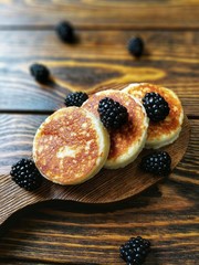 BlackBerry and pancake on aged wooden background with flowers and coffee