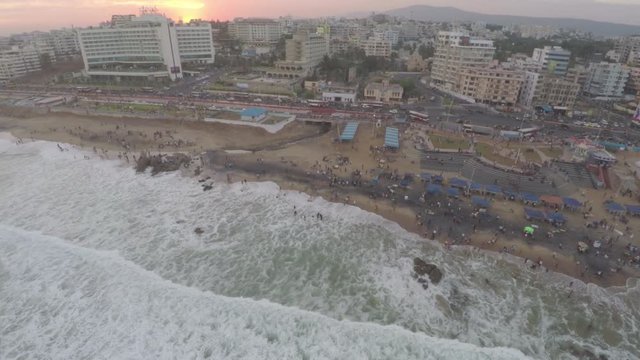 A beautiful aerial view of a city by the beach with waves crashing on the shore.