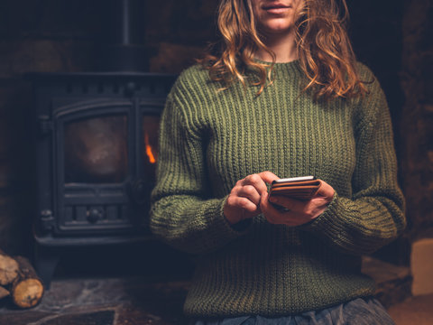 Young woman using smart phone by the fire