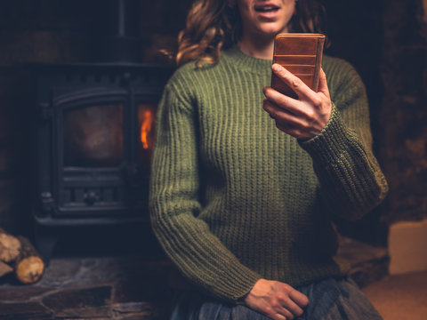 Young woman using smart phone by the fire