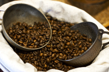 Coffee beans on a burlap suck. Silver coffee pot and cups