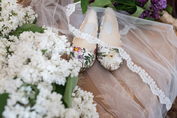 Shoes without heels with colorful flowers are covered with a veil. Wedding shoes 