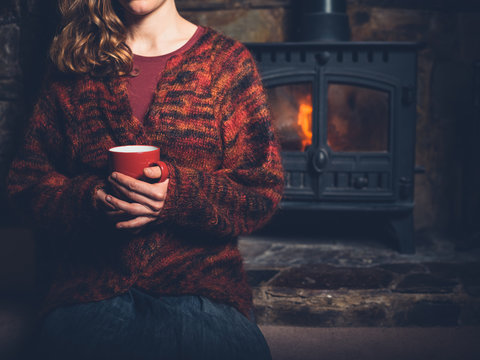 Woman in red jumper with mug by fire
