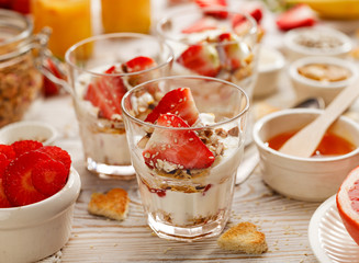 Natural yogurt with fresh fresh strawberries, granola, honey, nuts and seeds in a glass dishes. Delicious breakfast or dessert. Healthy eating concept. 