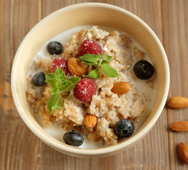 Oatmeal porridge in bowl topped with fresh blueberries and raspb