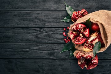 Fresh pomegranate in an old bag. On a wooden background. Top view. Copy space.