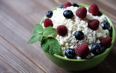 Cottage cheese in green bowl with raspberries  and blueberries o