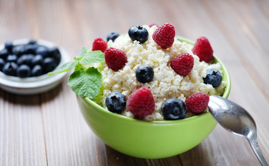 Cottage cheese in green bowl with raspberries  and blueberries o