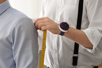Tailor taking man's measurements in atelier