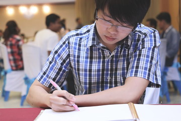 Young Asian guest man writing on memory book for blessing word to newlyweds couple in wedding ceremony