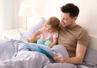 Father with little daughter reading bedtime story at home