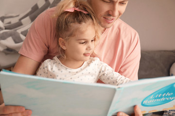 Father and his daughter reading book on floor in children room