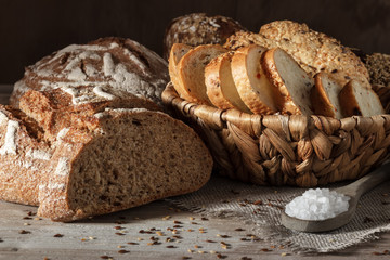 Set of wheat and rye bread with a spoon of salt on a wooden background
