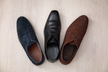 Different male shoes on wooden floor