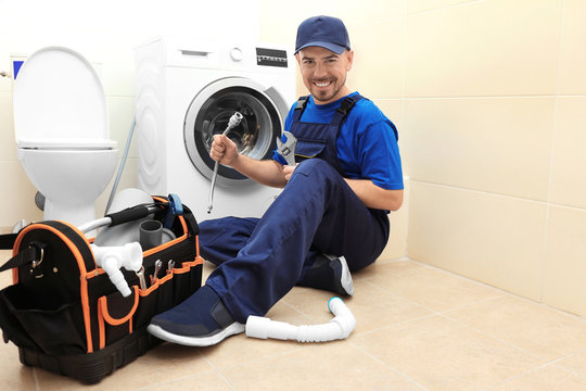 Plumber with set of tools working in bathroom