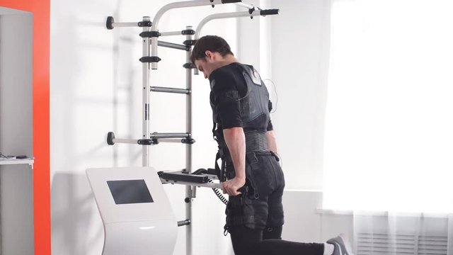 Male athlete select intensity of ems electro muscular stimulation machine.