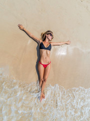 Fototapeta premium Top view of a woman at the tropical beach relaxing on the sand