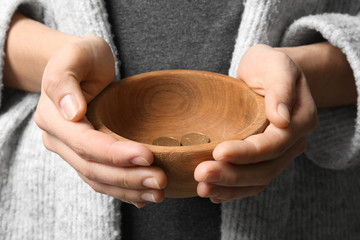 Poor woman with bowl and coins, closeup