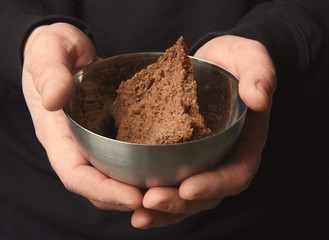 Poor man holding bowl with piece of bread, closeup