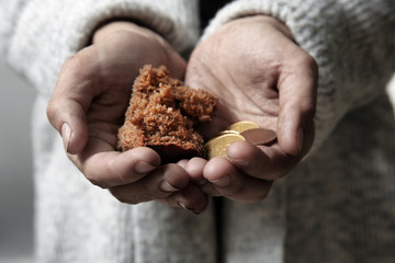 Poor woman holding piece of bread and coins, closeup