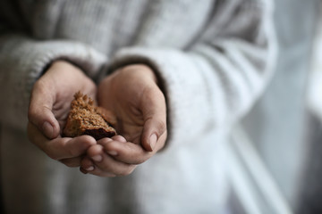 Poor woman holding piece of bread on blurred background - obrazy, fototapety, plakaty