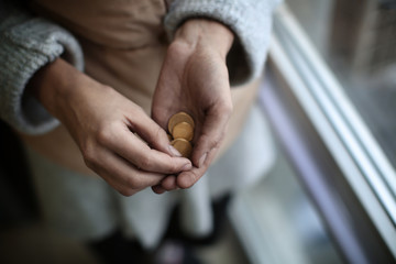 Poor woman holding coins, closeup