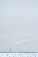 Fototapeta na wymiar Distant View Of Smoke Stack Emitting Pollution On Snow Covered Field Against Sky, Sofia, Bulgaria.