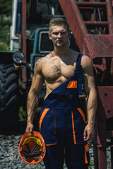 Obraz na płótnie Canvas Sexy man with nude torso near construction equipment or excavator
