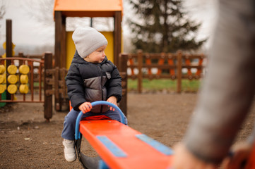 Little boy riding on the swing and looking away