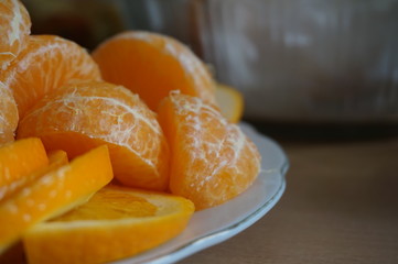 Naklejka na ściany i meble Slices of tangerines. Sliced orange. Delicious fruits on the table. Close-up photo. Macro mode. Useful vitamins. Blurred background. Design element.