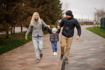 Parents walking down the street and having fun with a little son