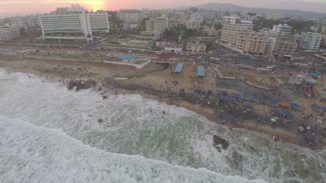 An aerial view of the sea with waves hitting the shores. A view of the city road with traffic moving in different directions.