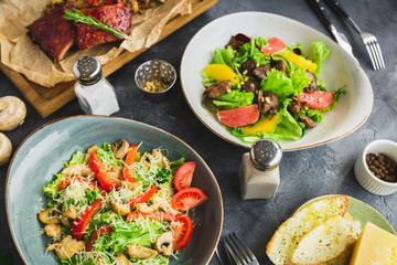 Grilled spare ribs with buckwheat, salad with citrus and grilled chicken liver, salad with tomato and vine  in a glass. Table with food in cafe.