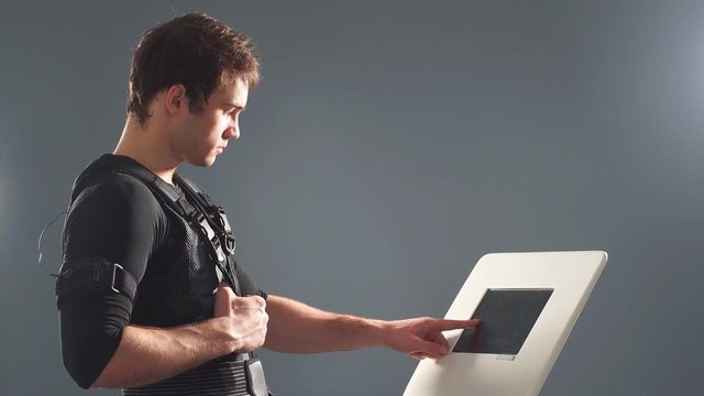 EMS, portrait of handsome man near electro muscle stimulation machine.