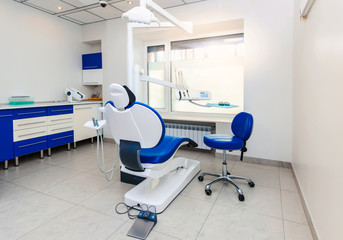 Interior of new modern dental clinic office room with chair in blue and white colors. Dentistry, stomatology, medicine medical equipment concept in teeth cabinet