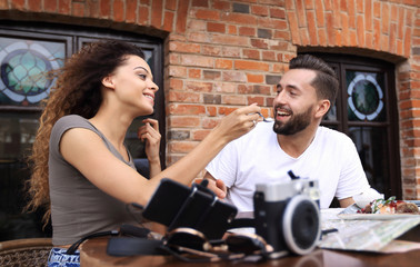 Young tourists eating breakfast at restaurant table outside side