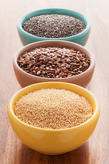 Chia, quinoa and flax seeds in a colorful bowls on a wooden background.
