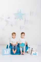 adorable little kids sitting on blue knitted plaid with book and rabbit cards, easter concept