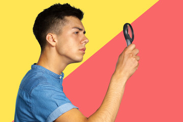 portrait of a young man looking through a magnifying glass