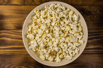 Bowl with popcorn on wooden table