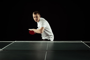 young tennis player in uniform practicing in table tennis isolated on black
