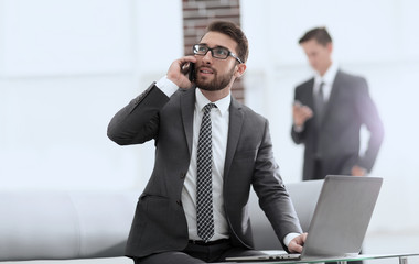 Confident young man talking on phone in office