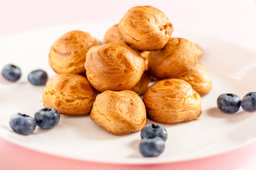 Homemade profiteroles served with blueberries on a white plate