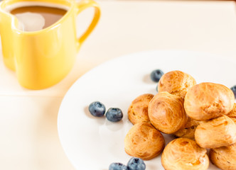 Homemade profiteroles served with blueberries on a white plate