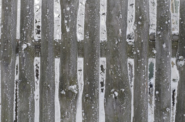 The peasant frozen old wooden fence covered with snow flakes in some province