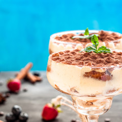 Italian dessert tiramisu in a glass on a blue background.
