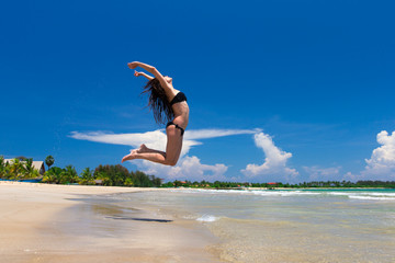 Happy woman in a jump on beach