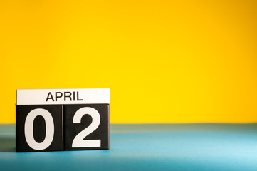April 2nd. Day 2 of april month, calendar on table with yellow background. Spring time, empty space for text