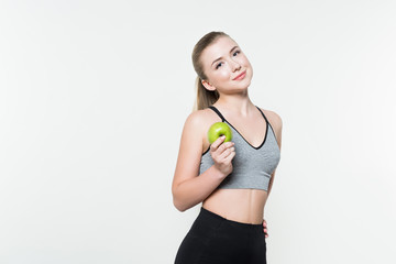 Young woman in sports top holding apple isolated on white