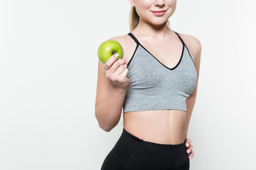 Cropped view of sportive girl holding apple isolated on white